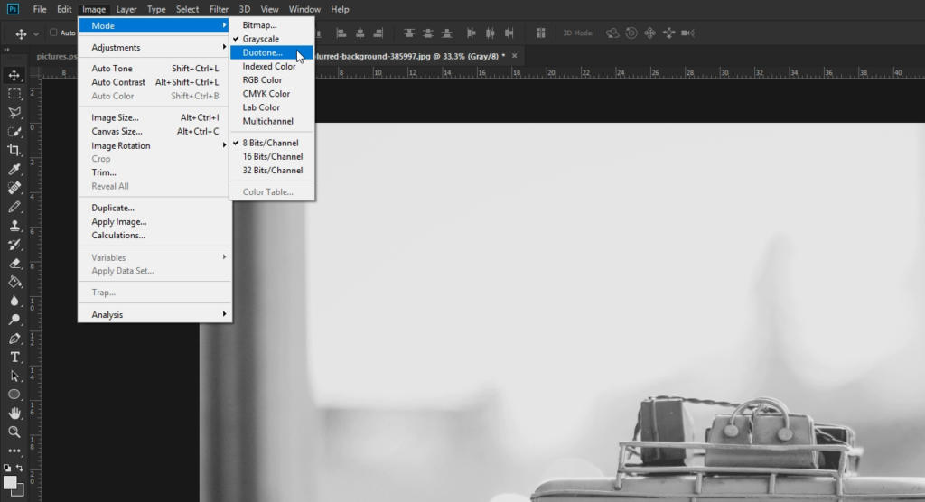 Et Photoshop-arbejdsområde viser billedmenuen åben, med markøren over tilstand og indstillingen gråtoner fremhævet, over et sepia-tonet sort-hvidt foto af en skrivemaskine.